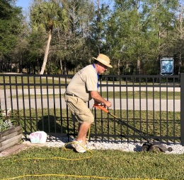 A man in a hat is cutting a fence with a saw