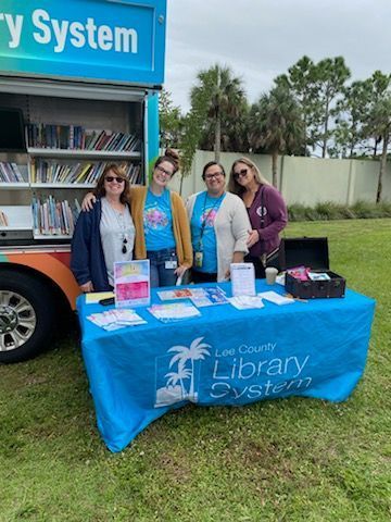 A group of women standing around a table in front of a library truck.