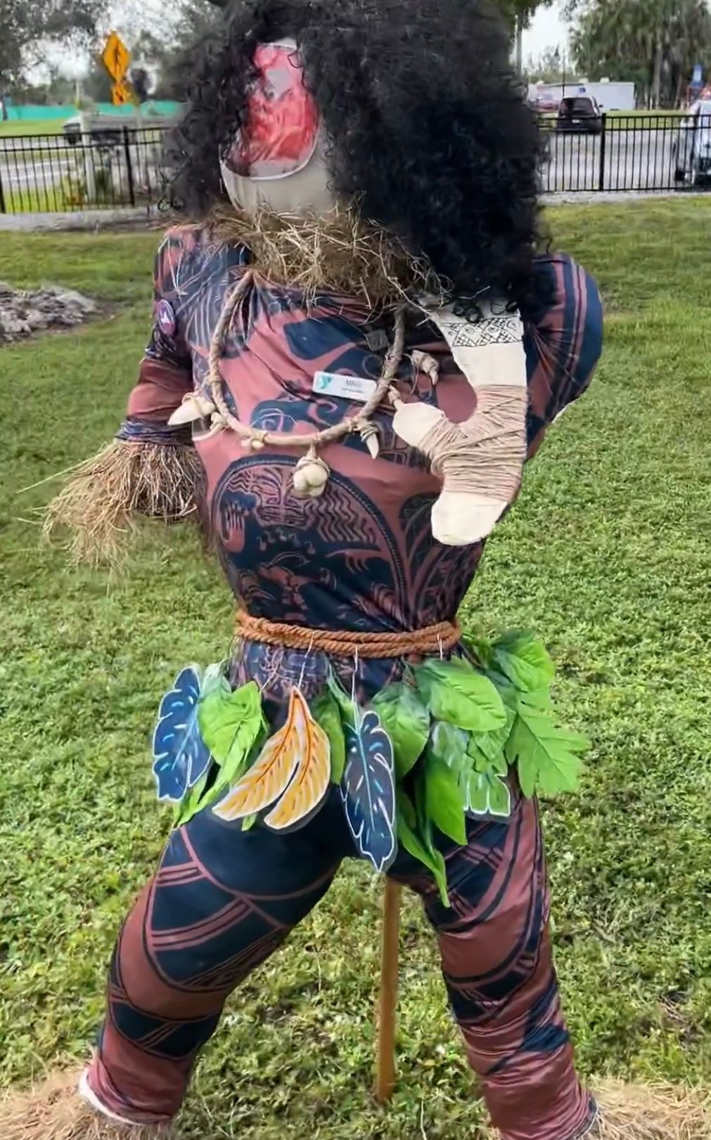 A scarecrow dressed as moana from moana is standing in the grass.