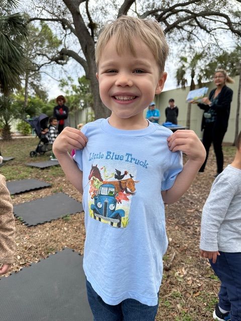 A young boy is wearing a little blue truck t-shirt.
