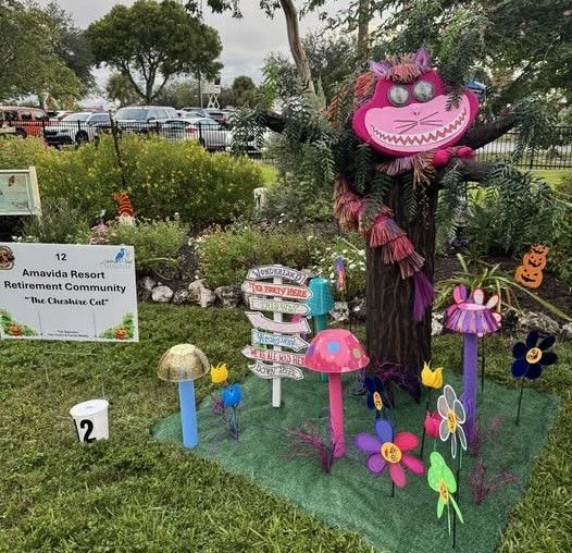 Cheshire Cat display with colorful mushrooms and flowers in a garden.