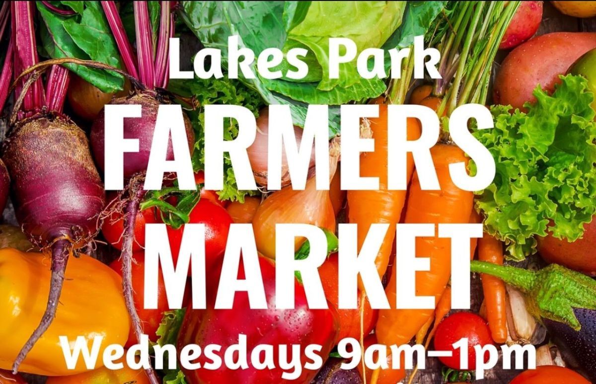 Lakes Park Farmers Market sign, surrounded by fresh produce: beets, carrots, tomatoes. Wednesdays, 9am-1pm.
