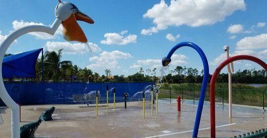 A water park with a blue umbrella and a bird spraying water.