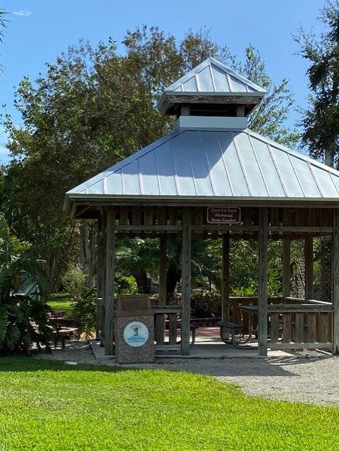 A gazebo with a metal roof is sitting in the middle of a grassy field.