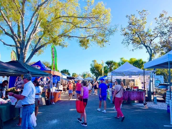 A group of people are standing in a parking lot at a farmer 's market.
