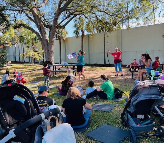 A group of people are sitting on the grass in a park