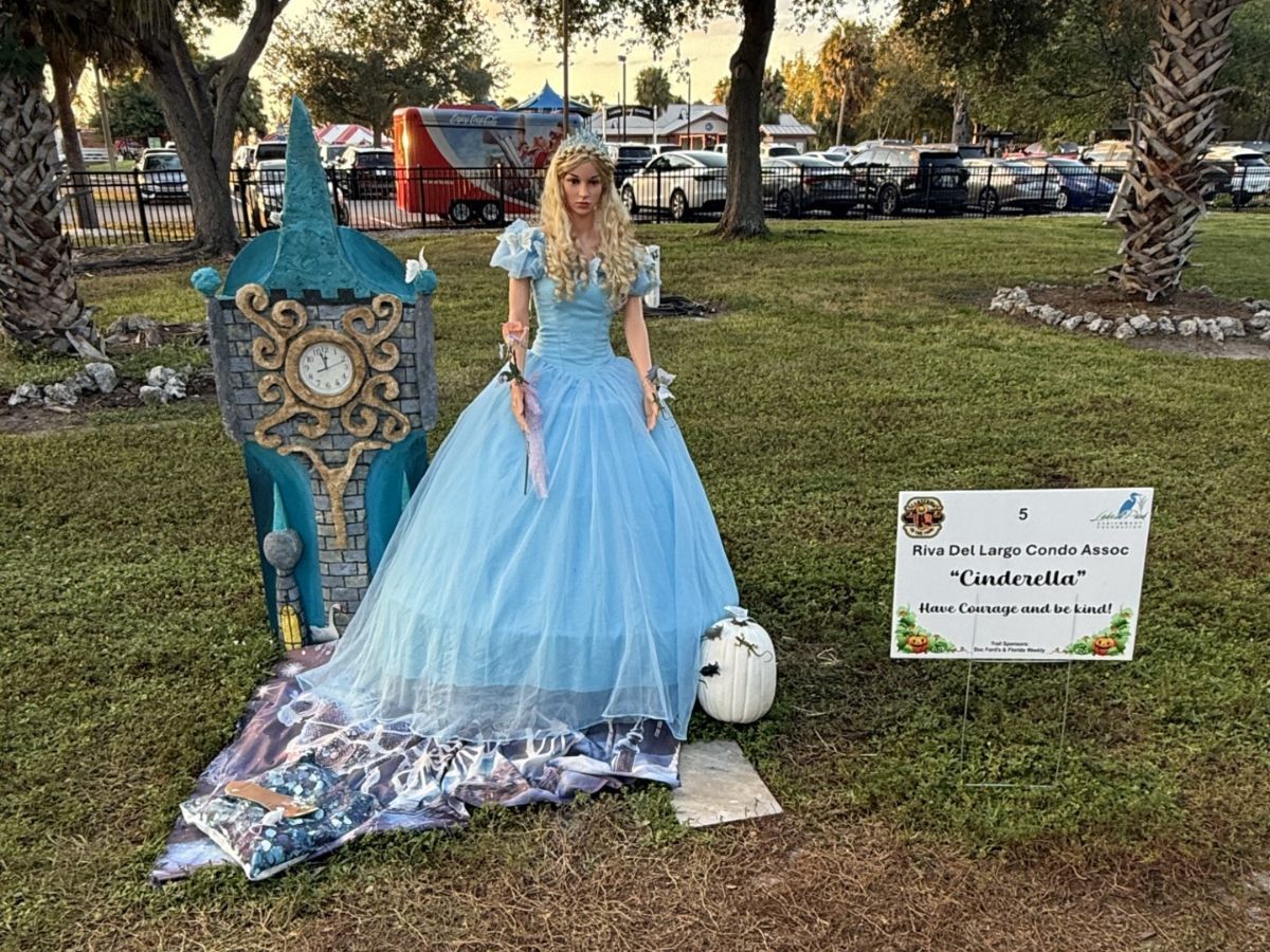 Cinderella display: A woman in a blue gown stands next to a clock tower. White pumpkin and sign.