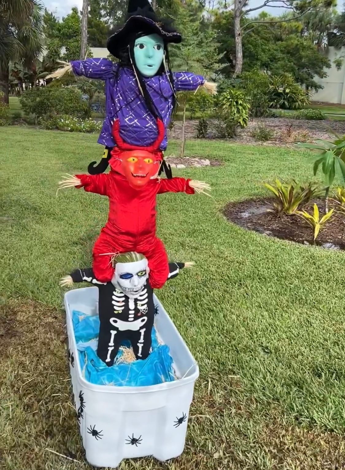 A scarecrow is sitting on top of a skeleton in a bucket.