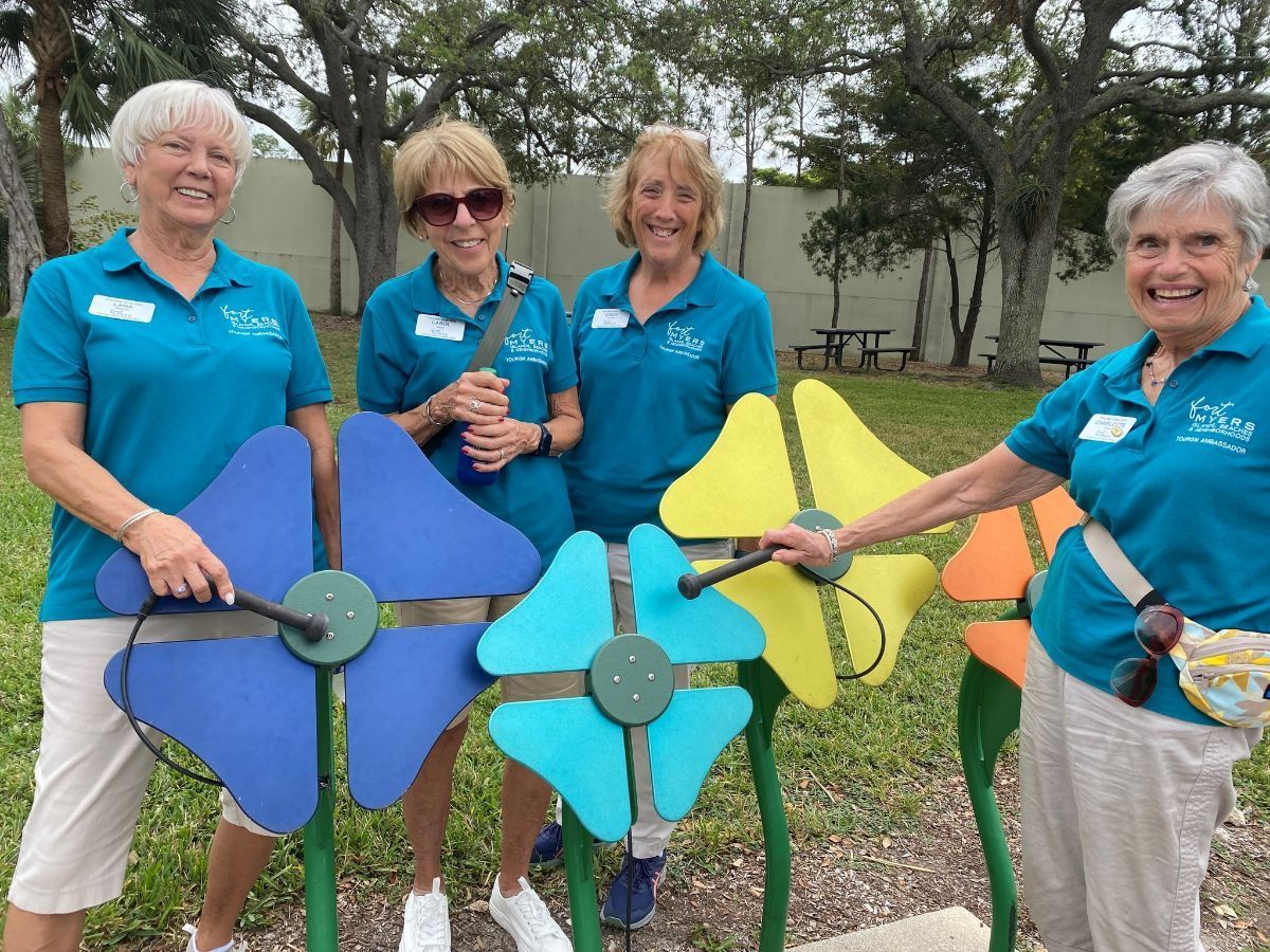 A group of women standing next to each other in front of colorful flowers