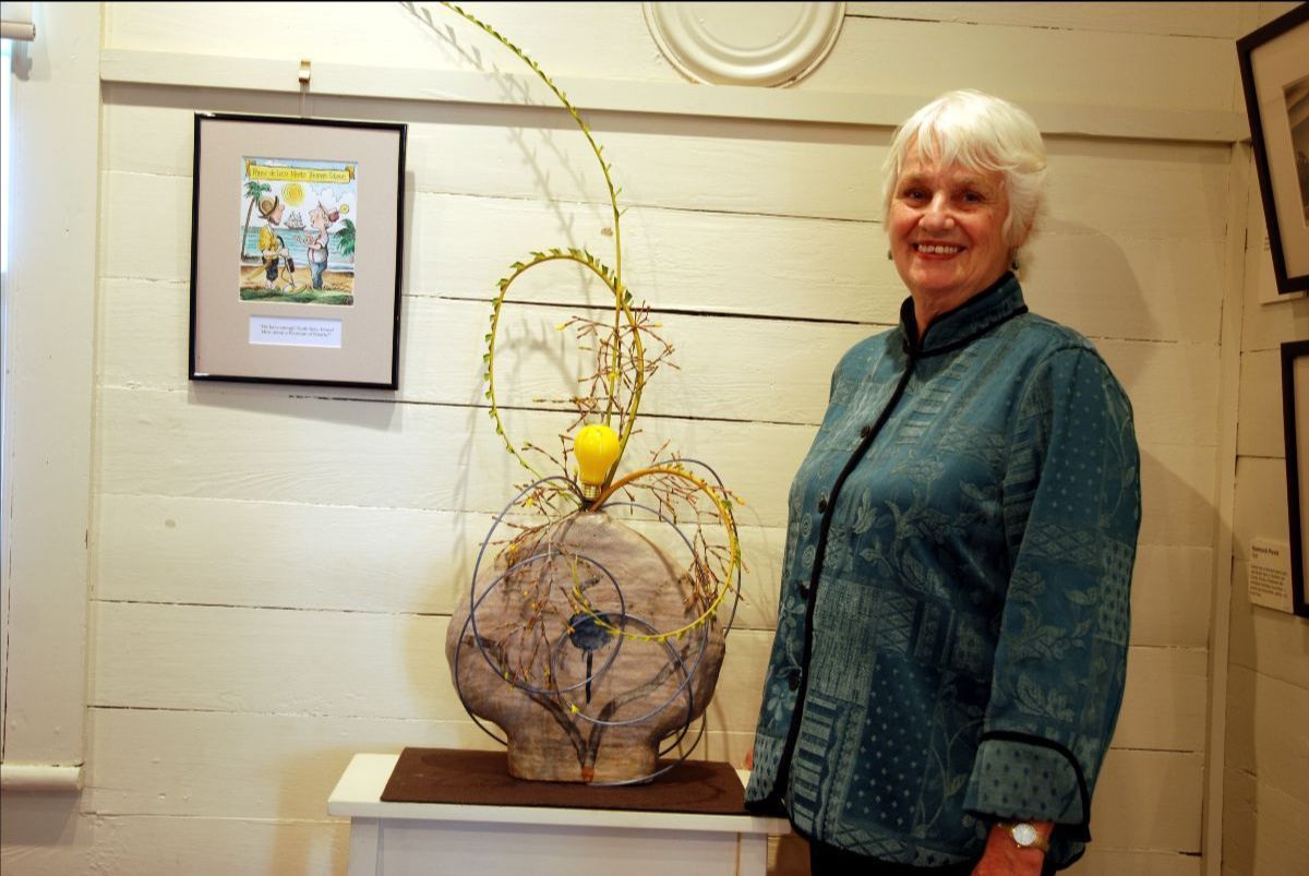 A woman in a blue jacket is standing next to a sculpture