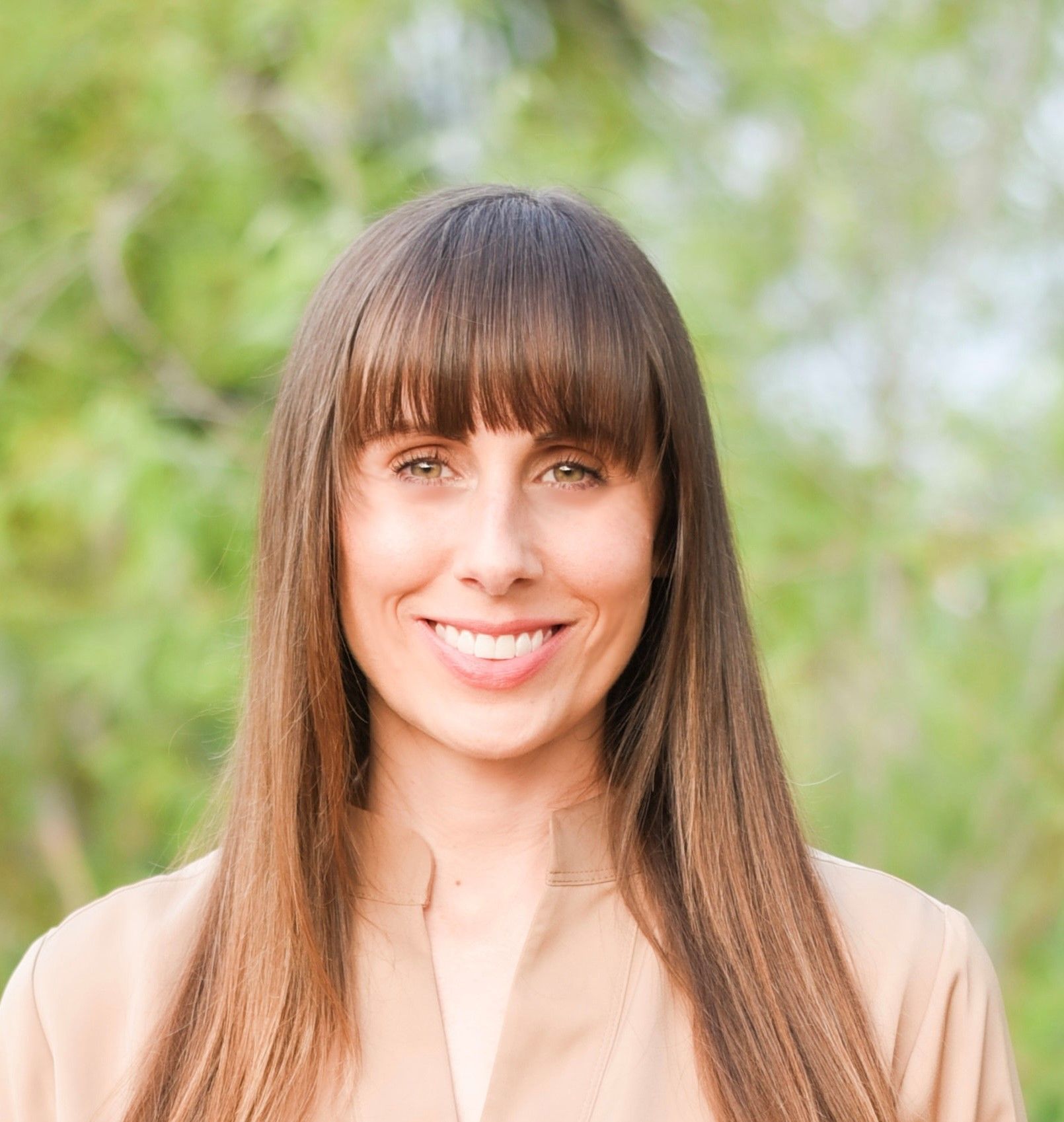 A woman with long hair and bangs is smiling for the camera.