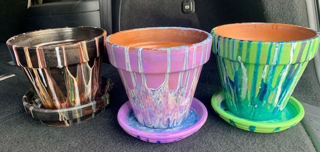 Three colorful pots are sitting in the back of a car.