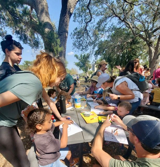 A group of people are sitting around a table in a park