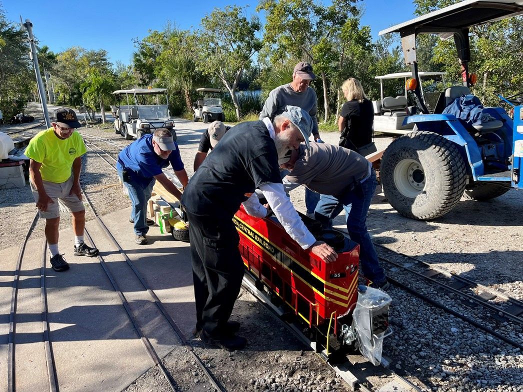 A group of people are working on a small train on a track.