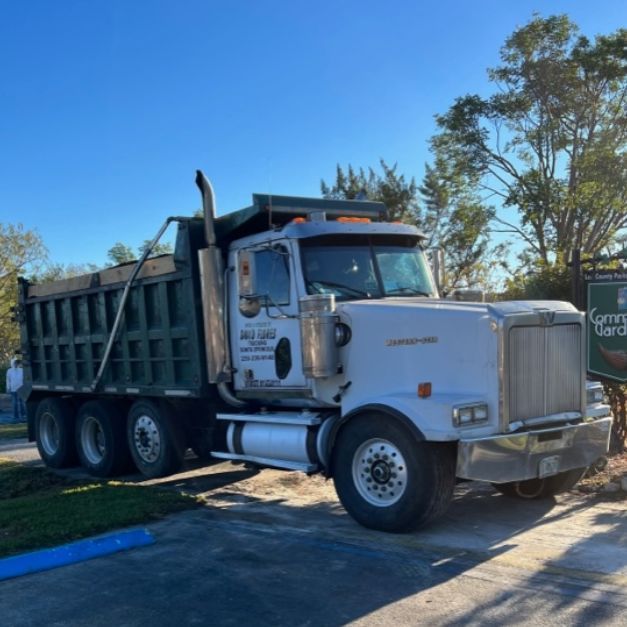 A dump truck is parked in front of a sign that says service garden