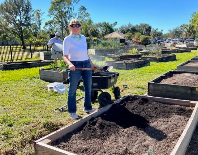 A woman is standing next to a wheelbarrow in a garden