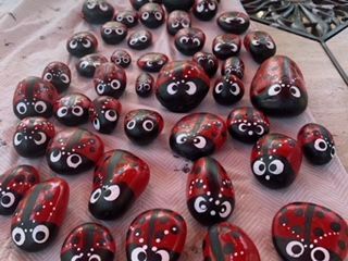 A bunch of ladybugs painted on rocks are sitting on a table.