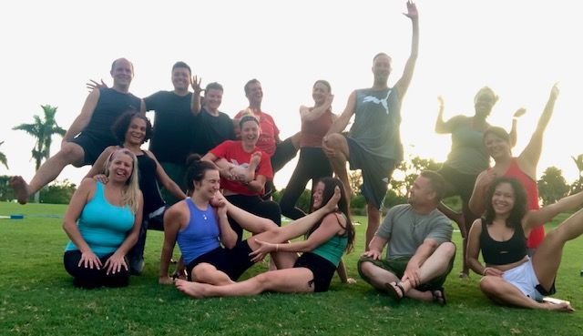 A group of people are posing for a picture while sitting on the grass.