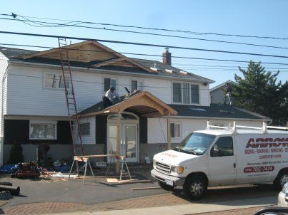 House exterior with roof work in progress and a white service van parked in front
