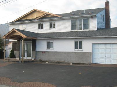 Two-story house with gray siding, white trim, and a garage, viewed from the driveway