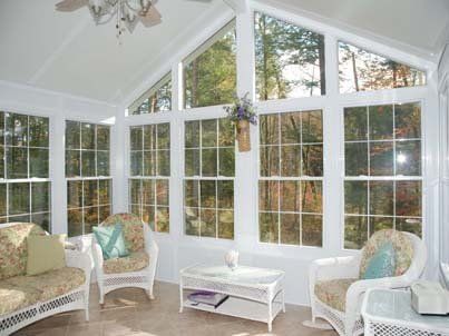 Bright sunroom with white wicker chairs, large windows, and light-colored decor.