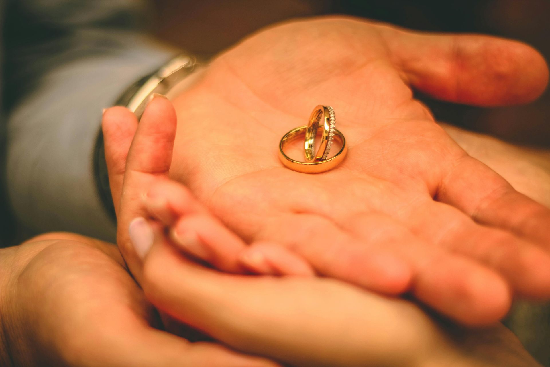 Two gold wedding rings rest on an open palm.