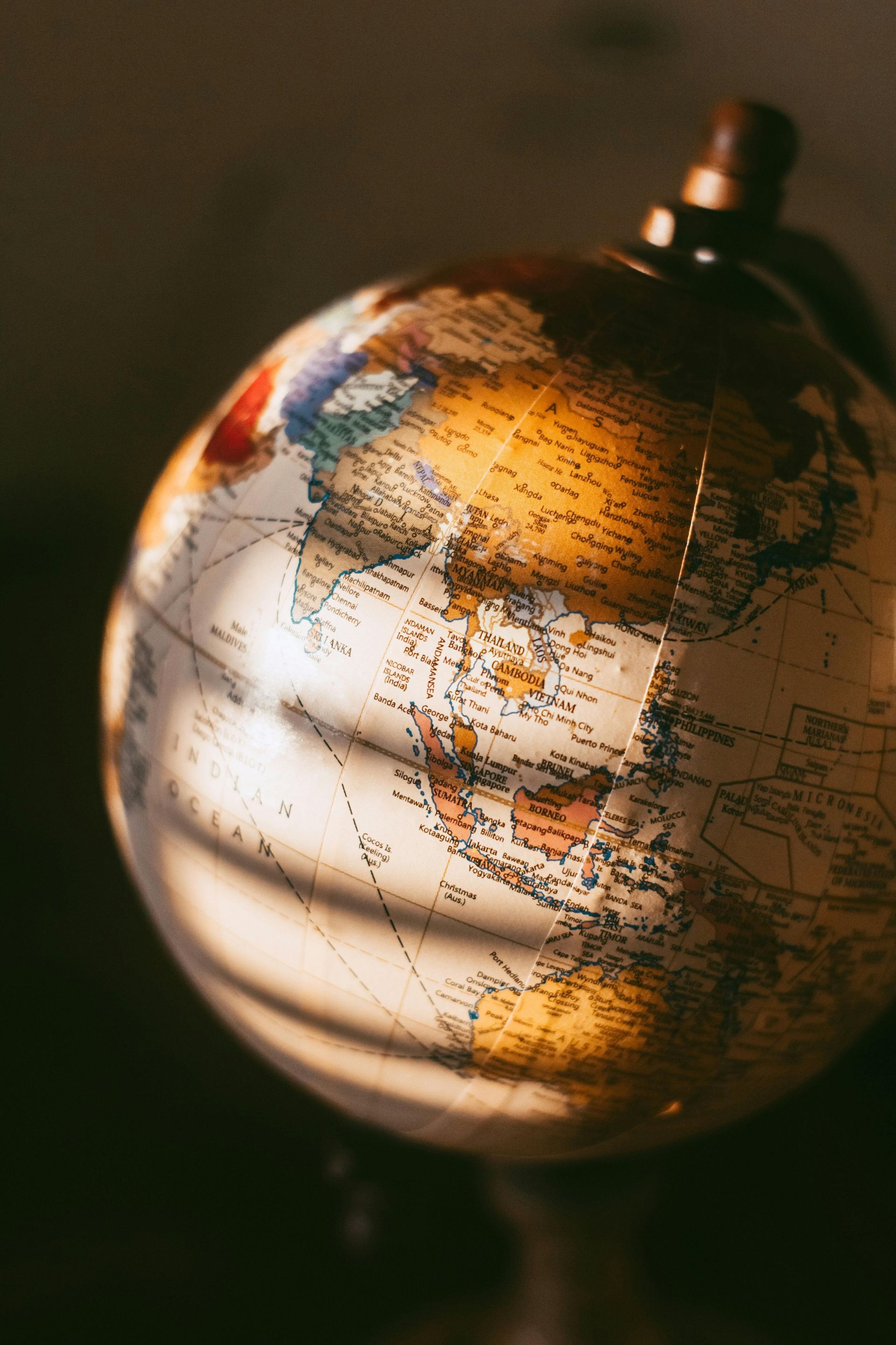 A globe sits against a dark background, illuminated by soft light that casts gentle shadows across the surface.
