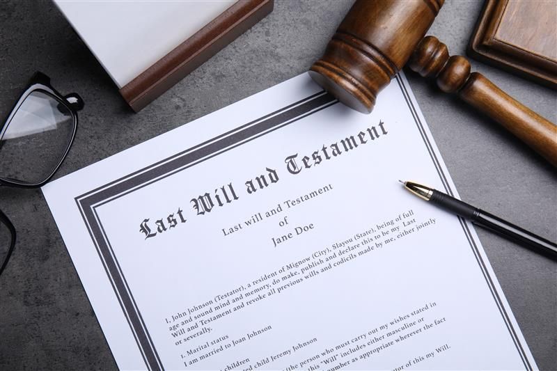 A wooden gavel, eyeglasses, and pen rest on a