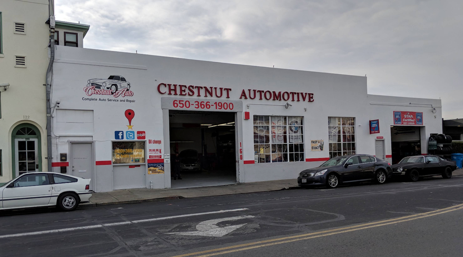 Street view of Chestnut Automotive garage with parked cars and open service bay under a cloudy sky | Chestnut Auto Repairs & Towing