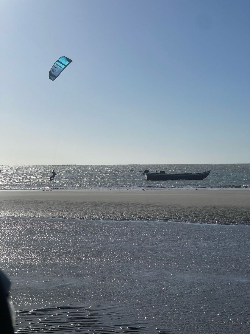 Uma pessoa está empinando uma pipa sobre o oceano