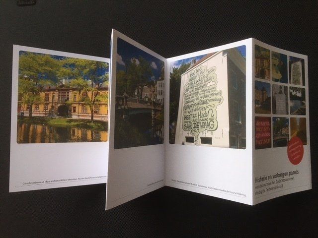 Gevouwen brochure met kleurenfoto's van gebouwen en straatbeelden.