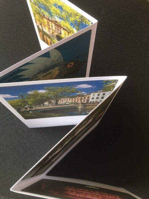 Op een gevouwen vel papier zijn kleurrijke foto's van gebouwen en een rivierlandschap te zien.