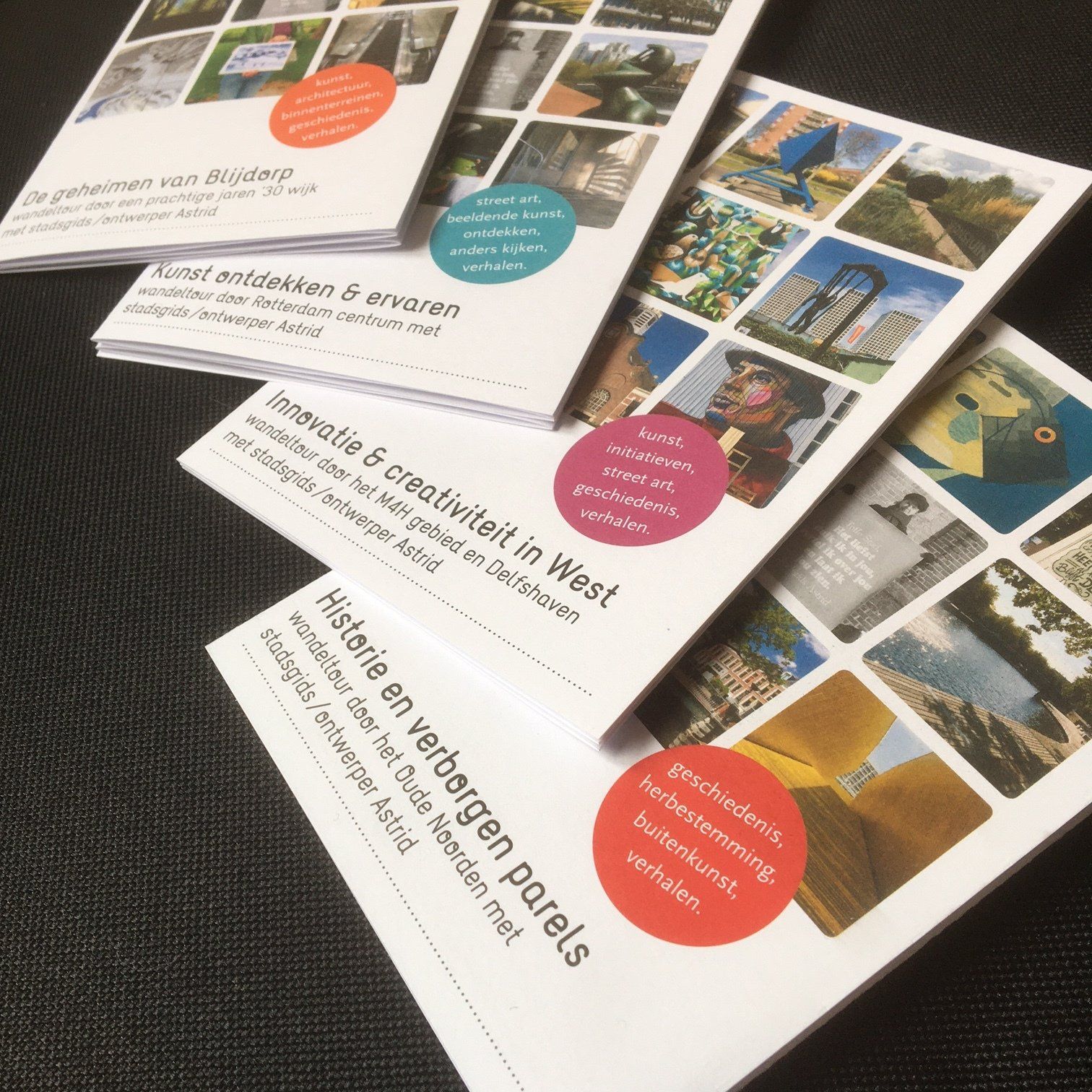 Vier brochures met kleurrijke cirkels, foto's en Nederlandse tekst, uitgespreid op een donkere achtergrond.