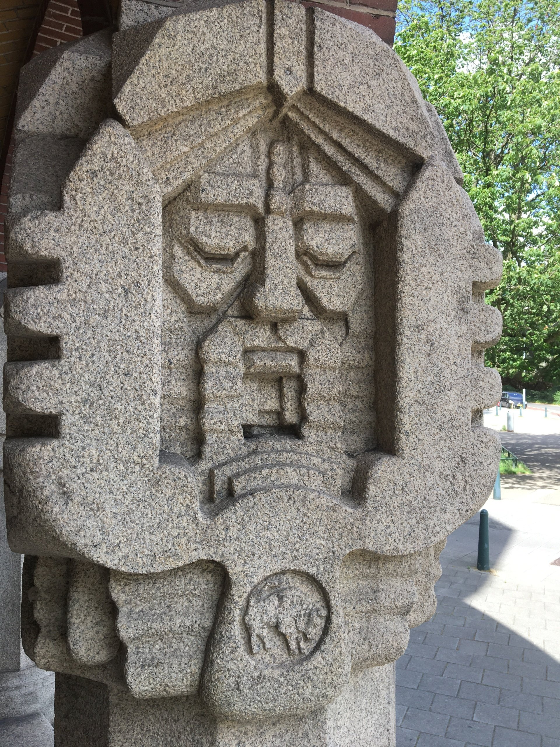 Een stenen beeldhouwwerk van een bebaard gezicht op een pilaar, mogelijk een historische figuur.
