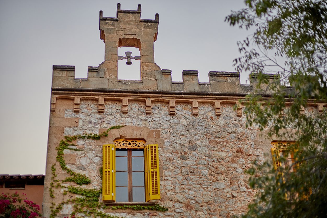 Un edificio de ladrillo con una torre encima y una ventana con contraventanas amarillas.