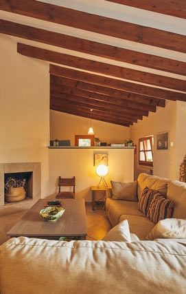 Una sala de estar con sofá, mesa, chimenea y vigas de madera.