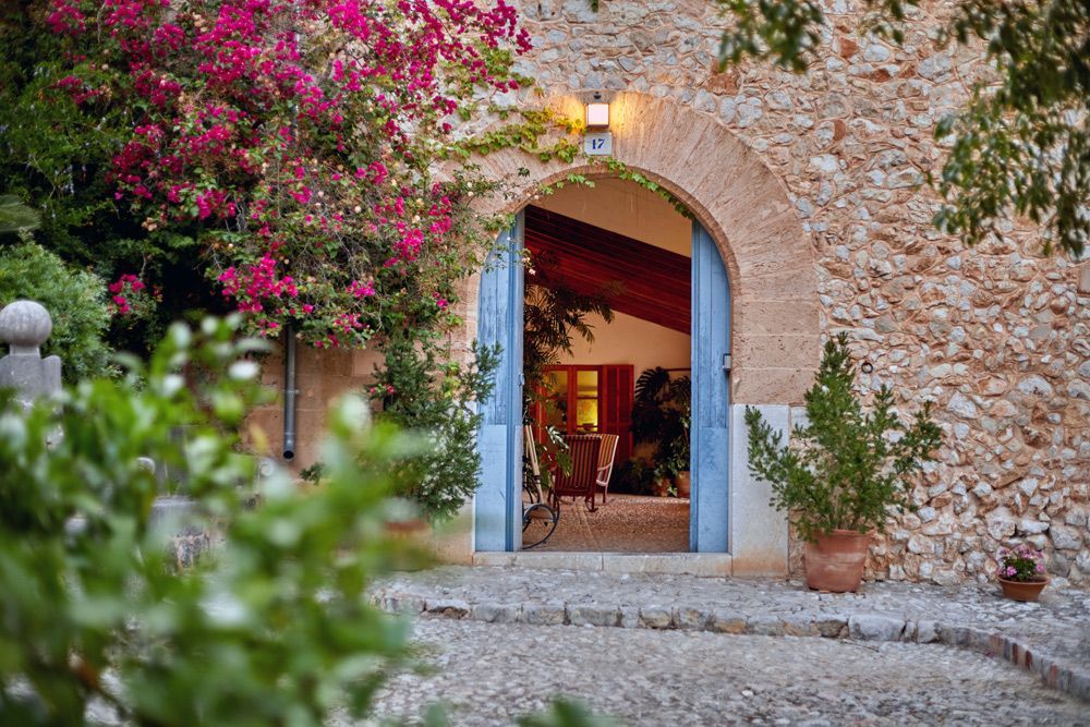 Un edificio de piedra con una puerta azul y flores rosas delante de ella.