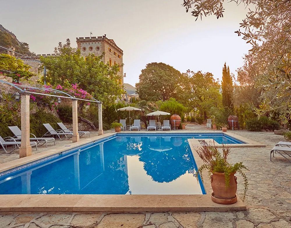 Una gran piscina con sillas y sombrillas alrededor.