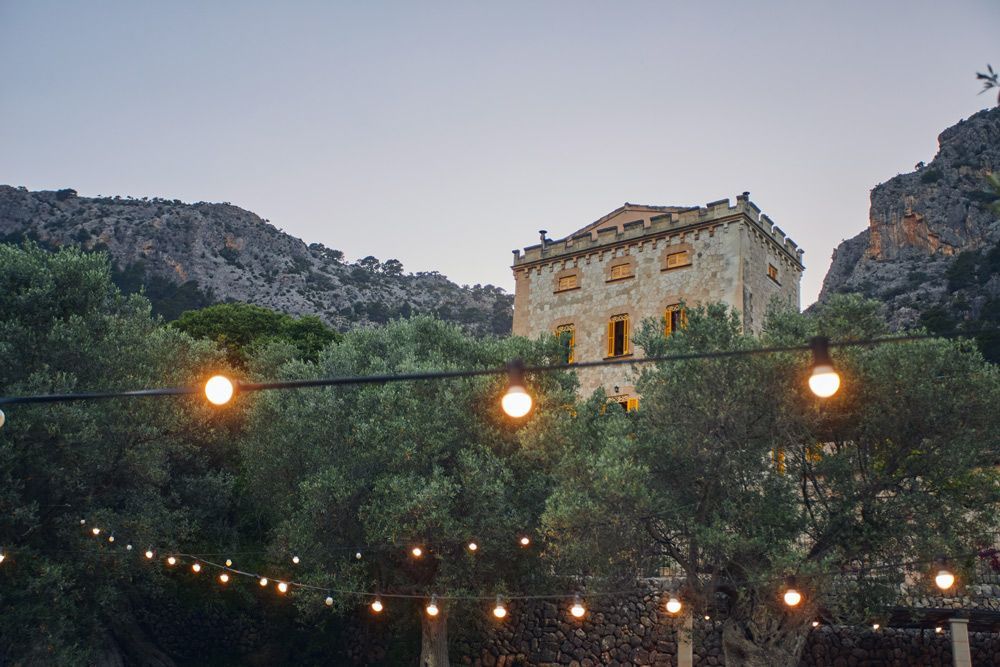 Una cadena de luces cuelga de un árbol frente a un castillo.