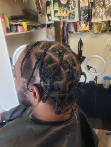 Close-up of braided hairstyle with silver beads in a salon chair beside a ring light and hair products