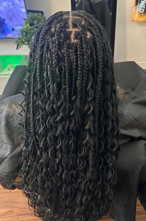 Back view of long black braided hair with a center part in a salon chair
