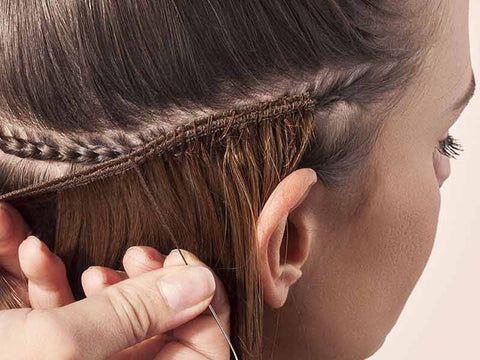 Close-up of a braided hairstyle being sewn in with a needle and thread