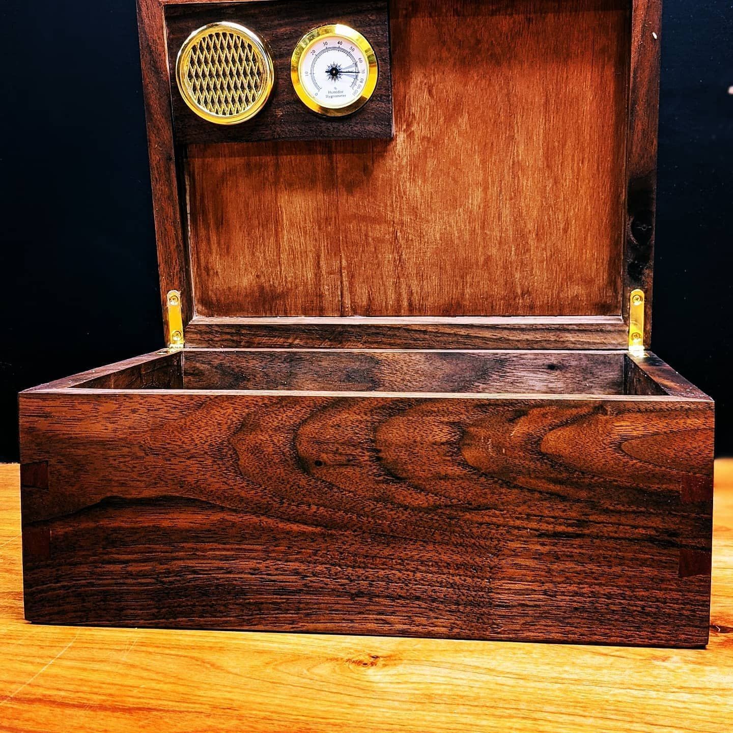 A wooden box with a humidifier on top of it is sitting on a wooden table.