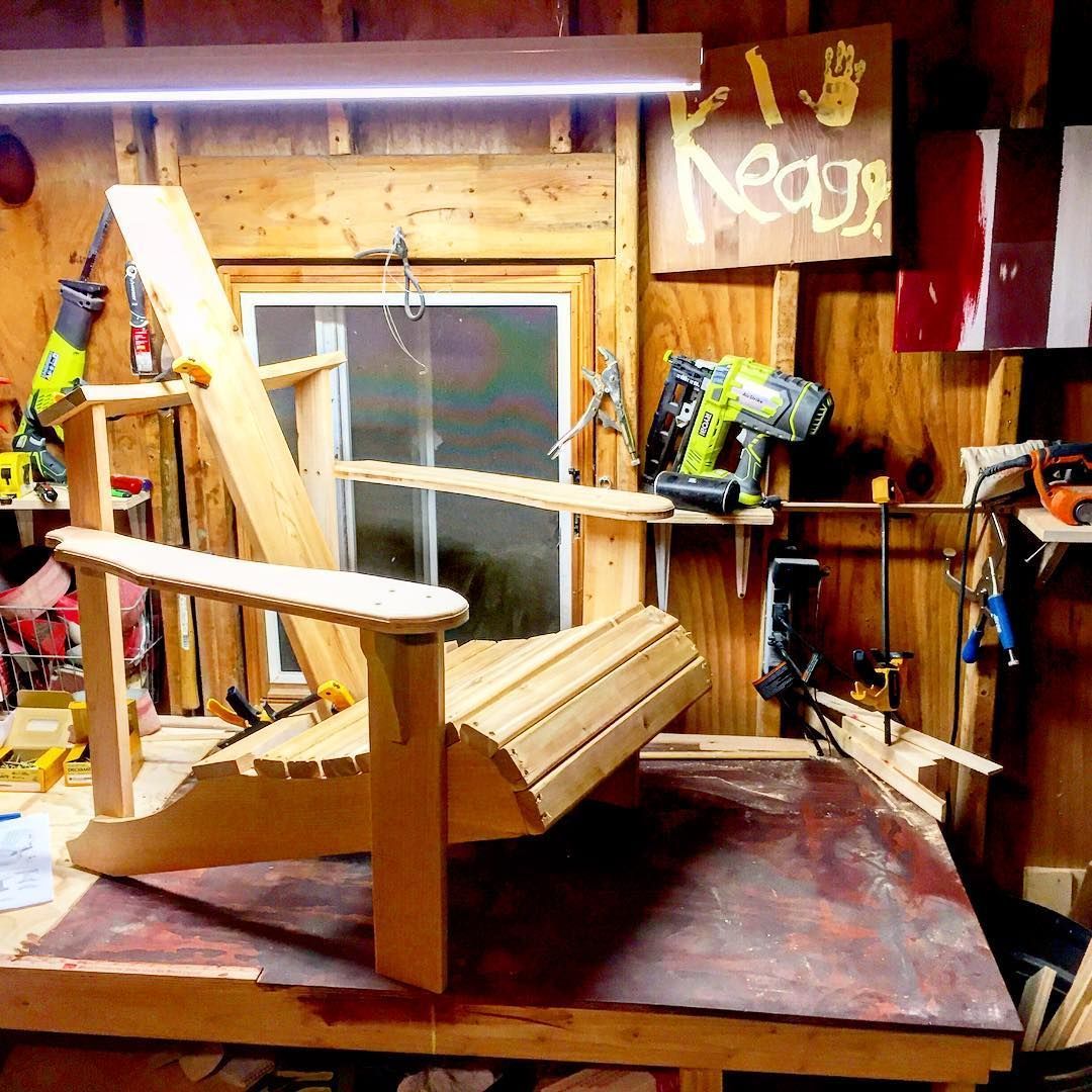 A wooden chair is sitting on top of a wooden table in a workshop.