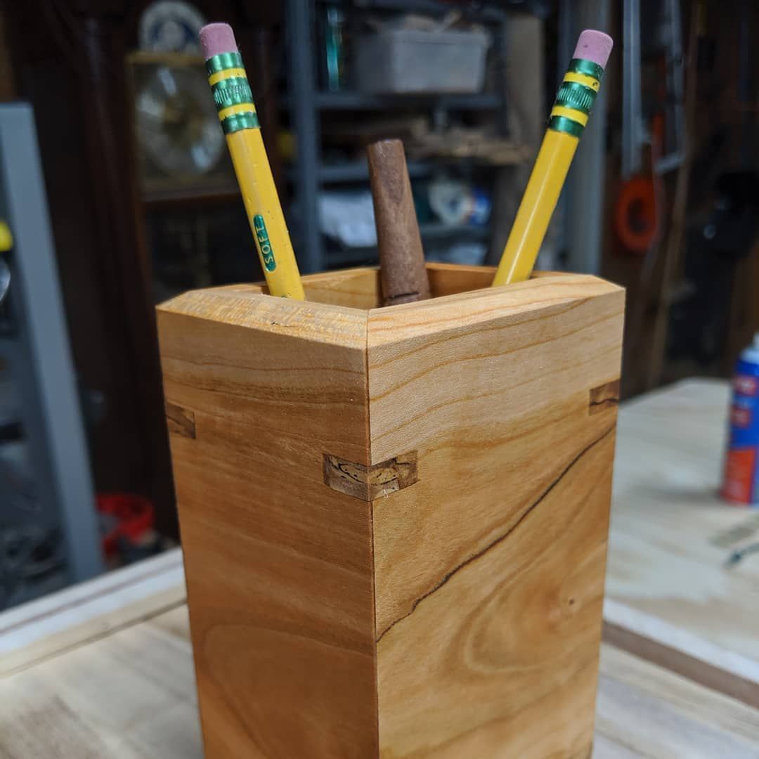A wooden pencil holder with two yellow pencils in it