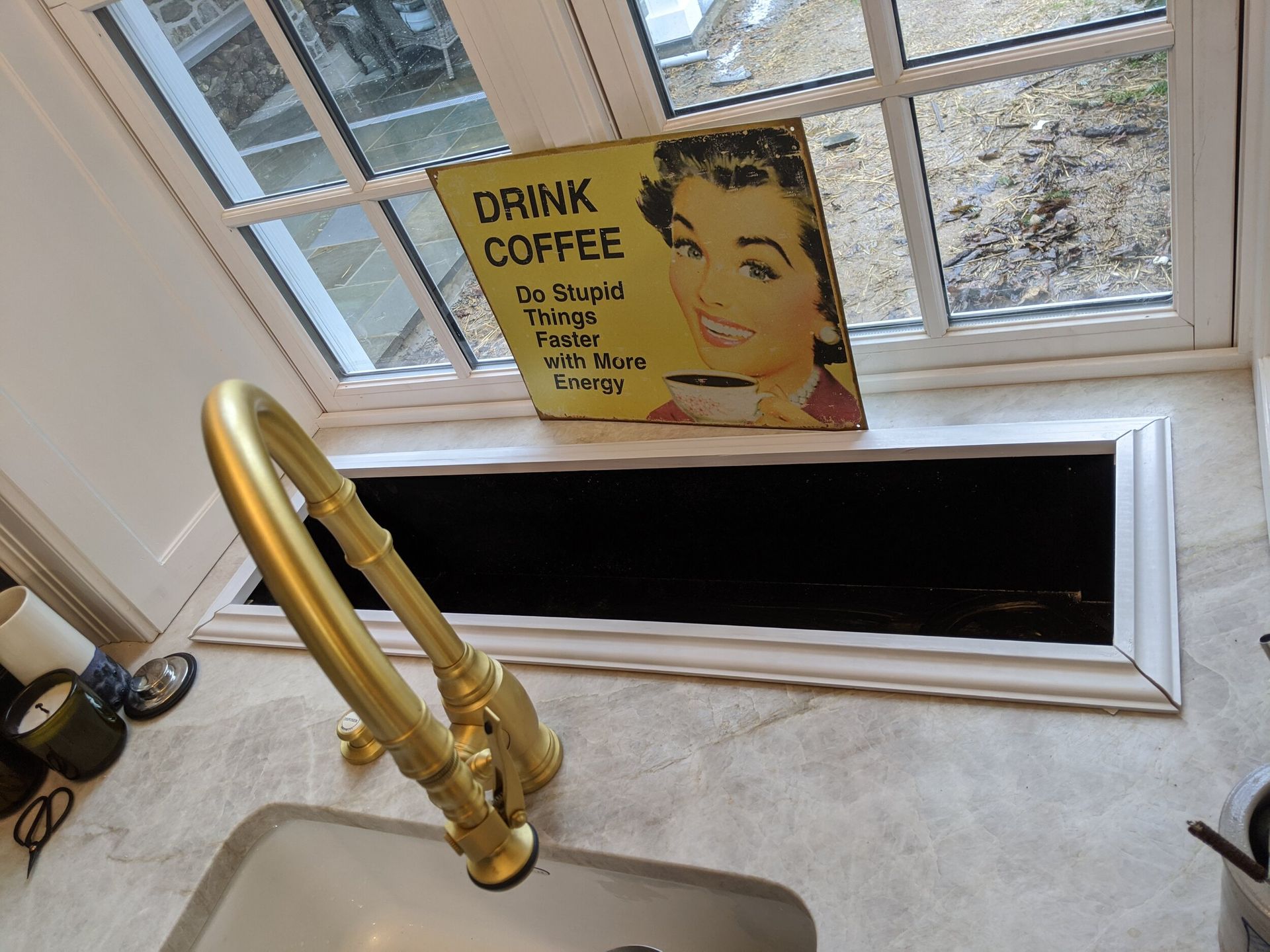 A kitchen sink with a sign that says drink coffee on it