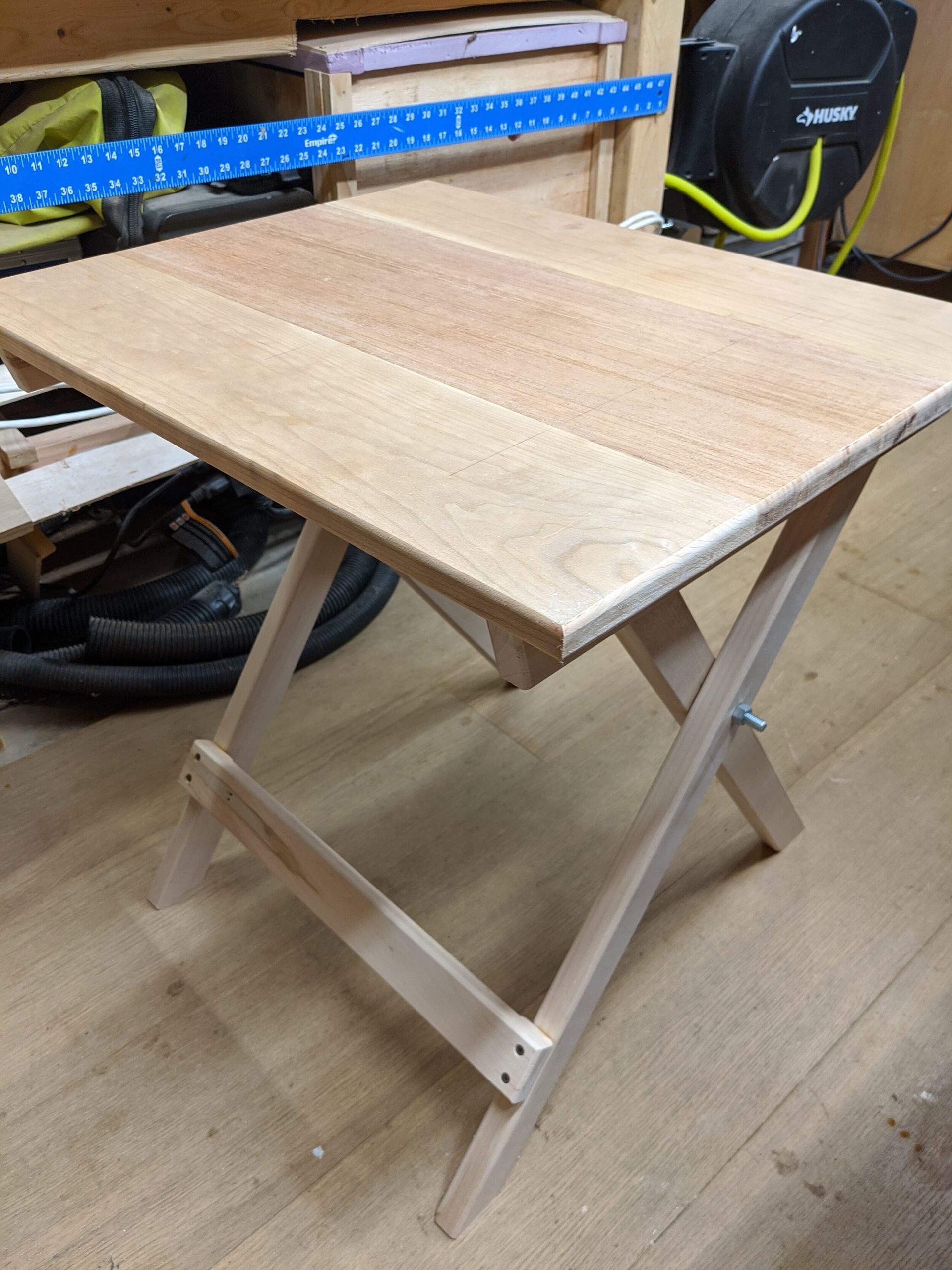 A wooden folding table is sitting on a wooden floor