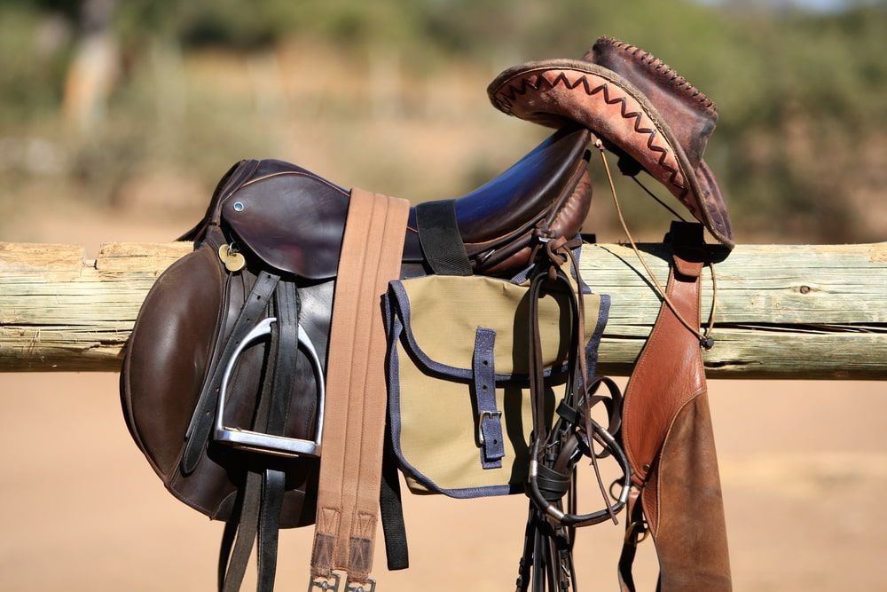 A Saddle And Cowboy Hat Are Hanging On A Wooden Fence — Wauchope Rural Centre In Wauchope, NSW