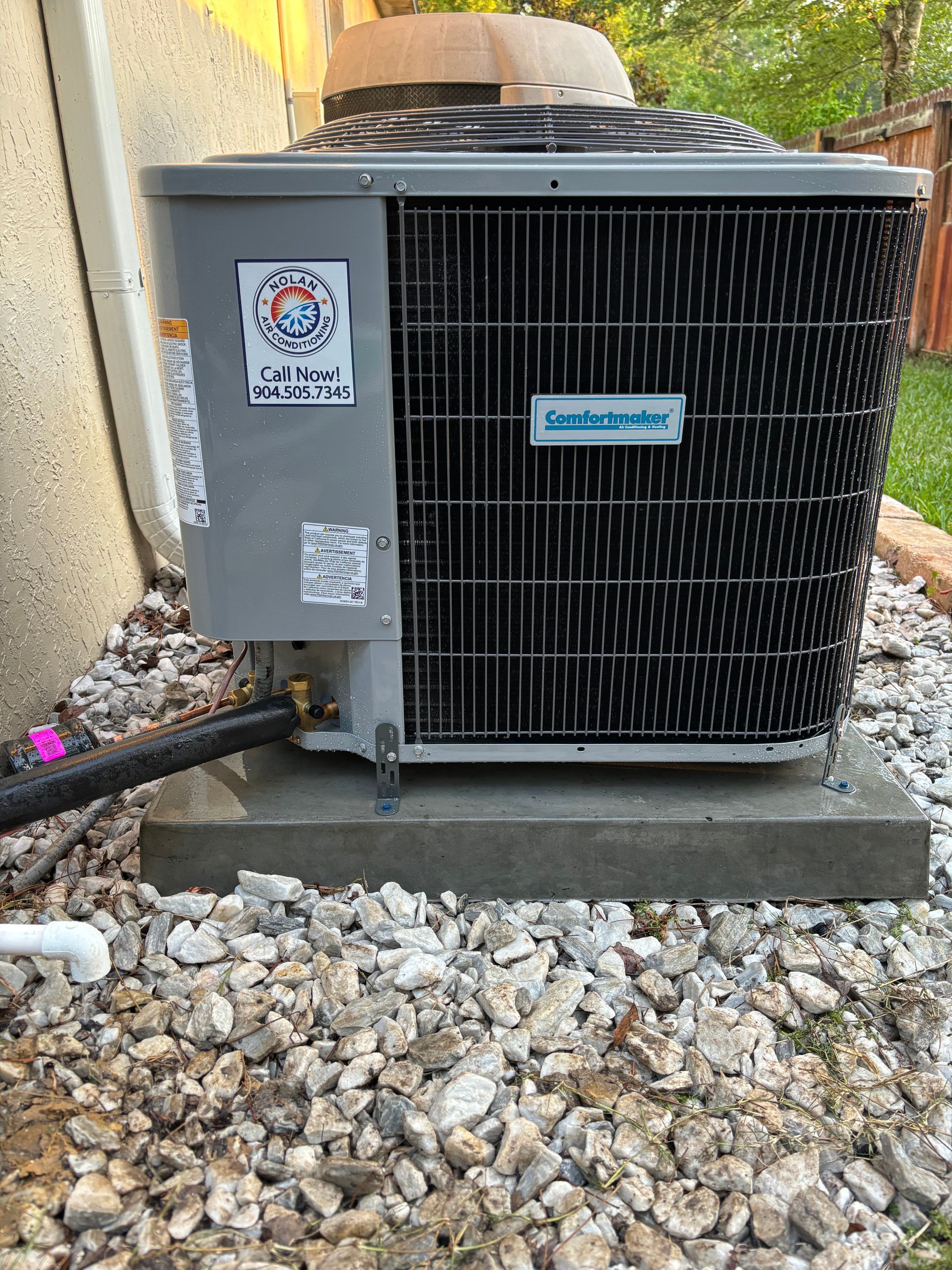 A large air conditioner is sitting on top of a pile of rocks.