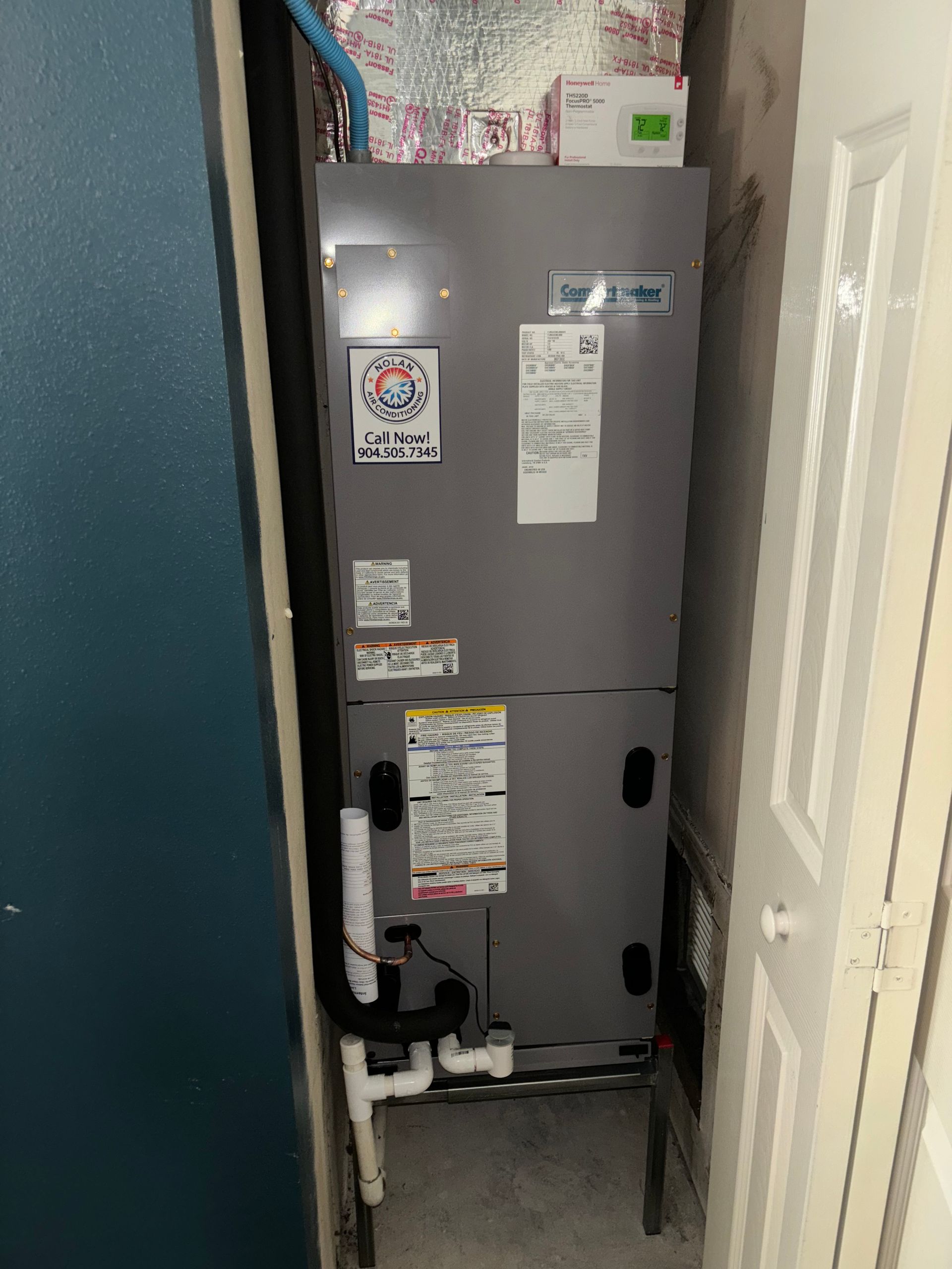 A refrigerator is sitting in a corner of a room next to a door.